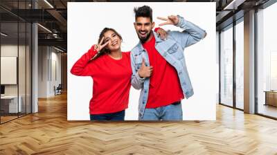 Smiling young indian couple making victory or peace sign on white background Wall mural